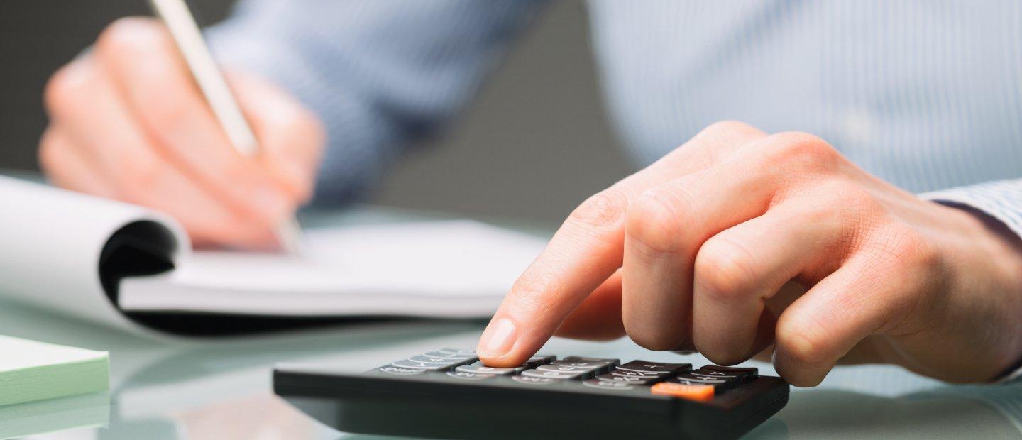 Hands writing in a notebook and using a calculator